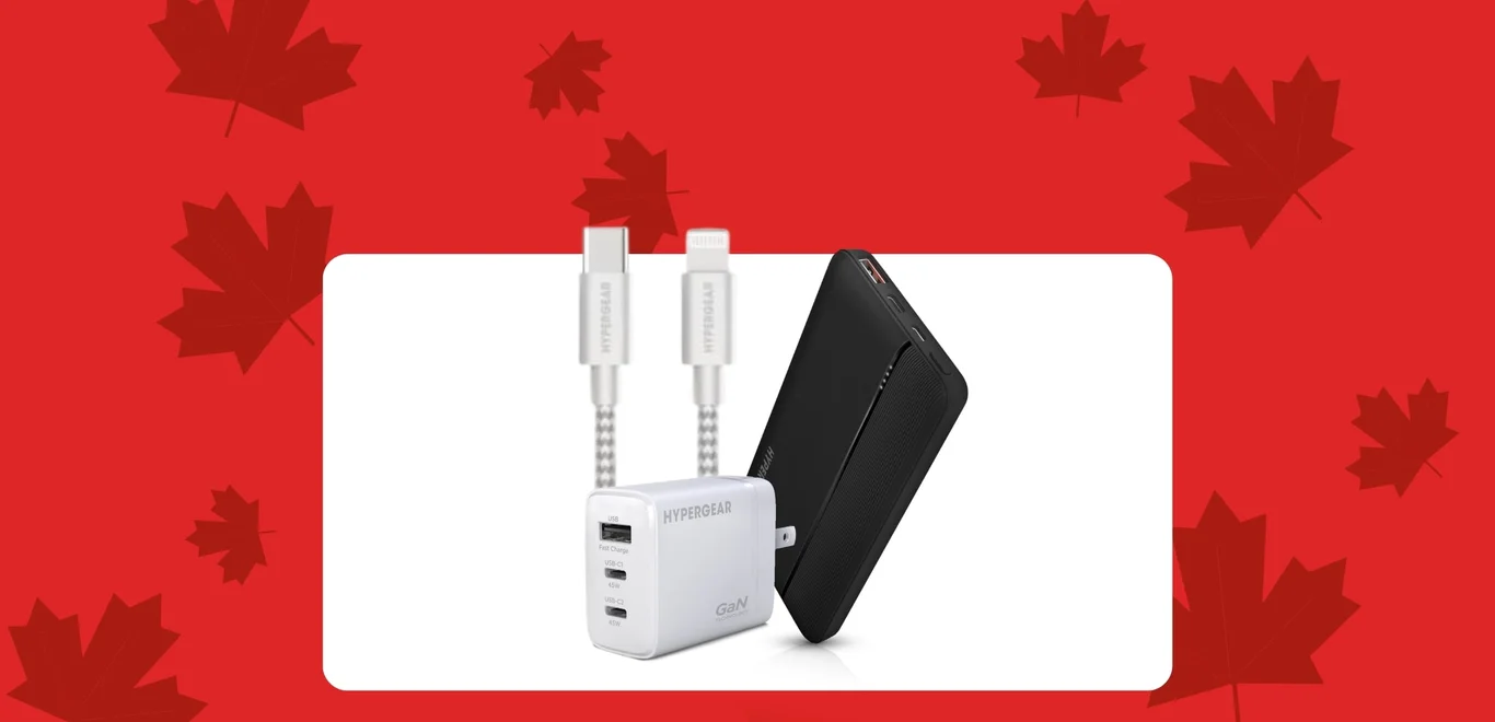 Des câbles Hypergear dans une boîte derrière une batterie externe Hypergear noire, à côté d'un bloc de recharge de téléphone Hypergear blanc, à l'intérieur d'un contenant blanc, sur un fond rouge couvert de feuilles d'érable rouge foncé.